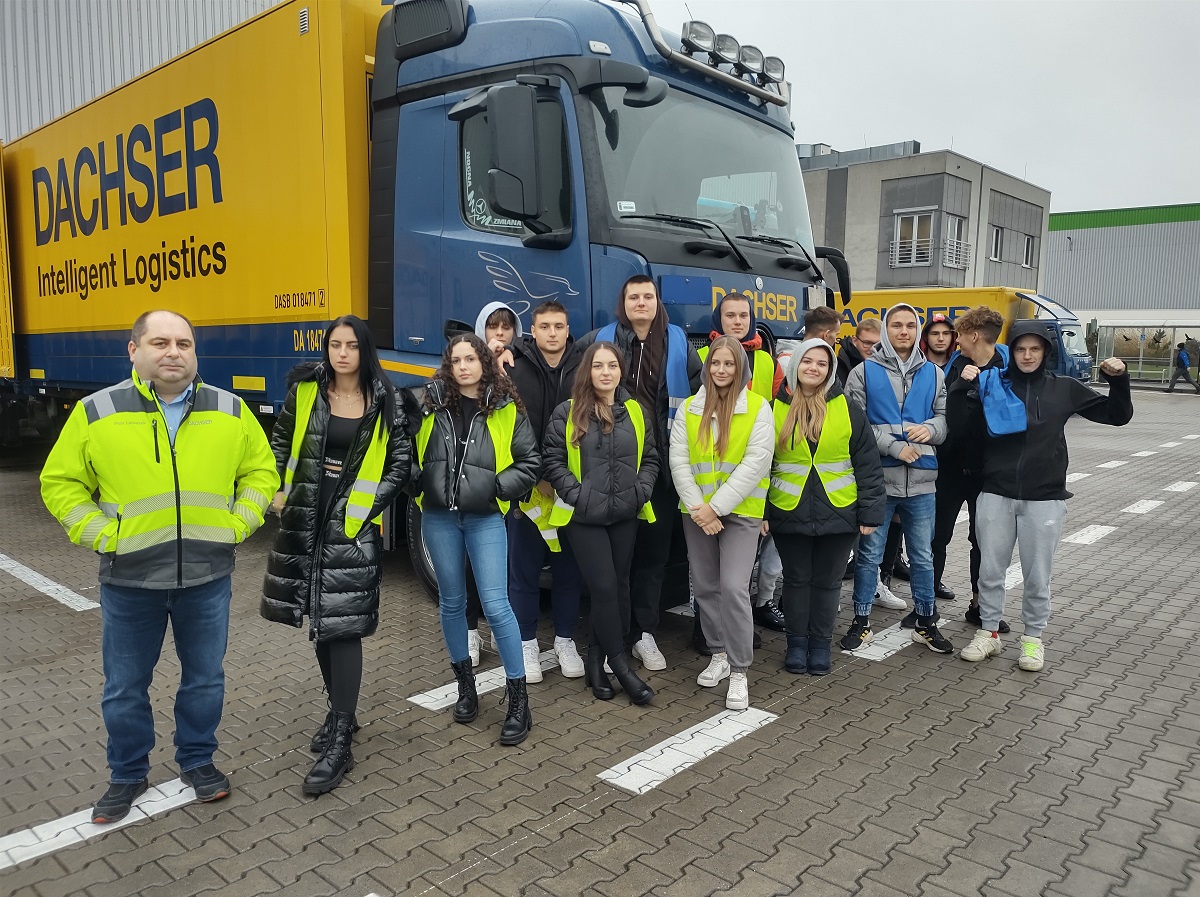 uczniowie stoją w grupie na tle ciężarówki z logo DACHSER